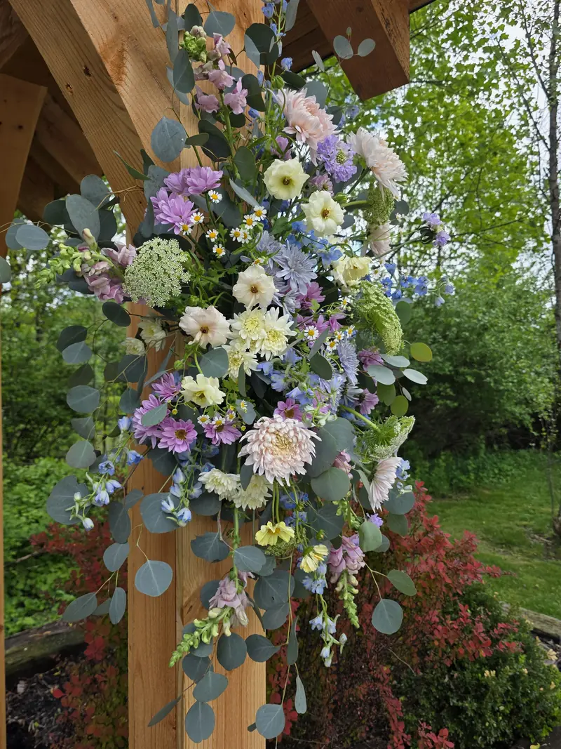A garden-inspired installation of lavender and blush flowers with eucalyptus on a wooden wedding arch
