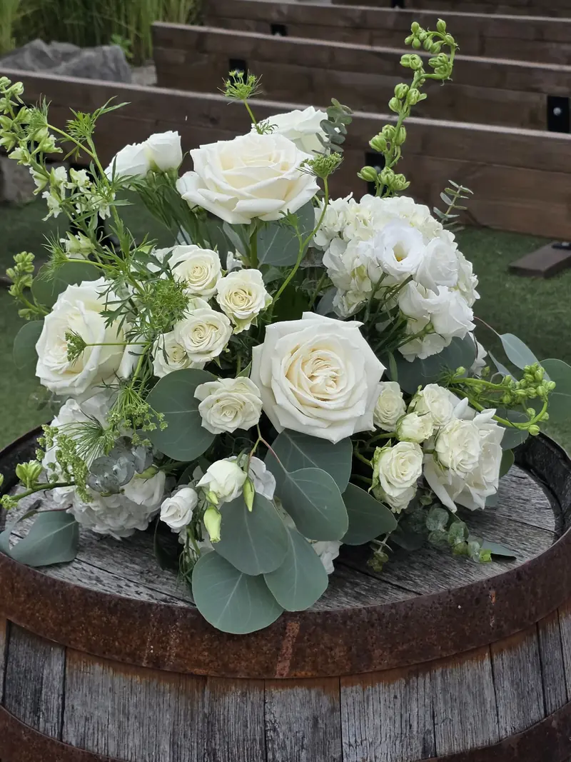 White roses and delicate white flowers arranged with eucalyptus